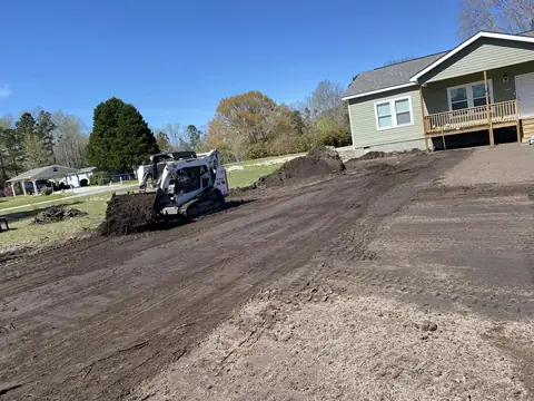 Skid steer finishing grade along the foundation — Coastal Clearing & Debris, Brunswick County NC