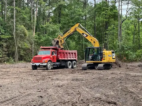 Truck and excavator working a cleared lot together — Coastal Clearing & Debris, Brunswick County NC