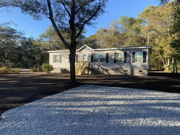 Finished gravel driveway curving to a home under a mature oak